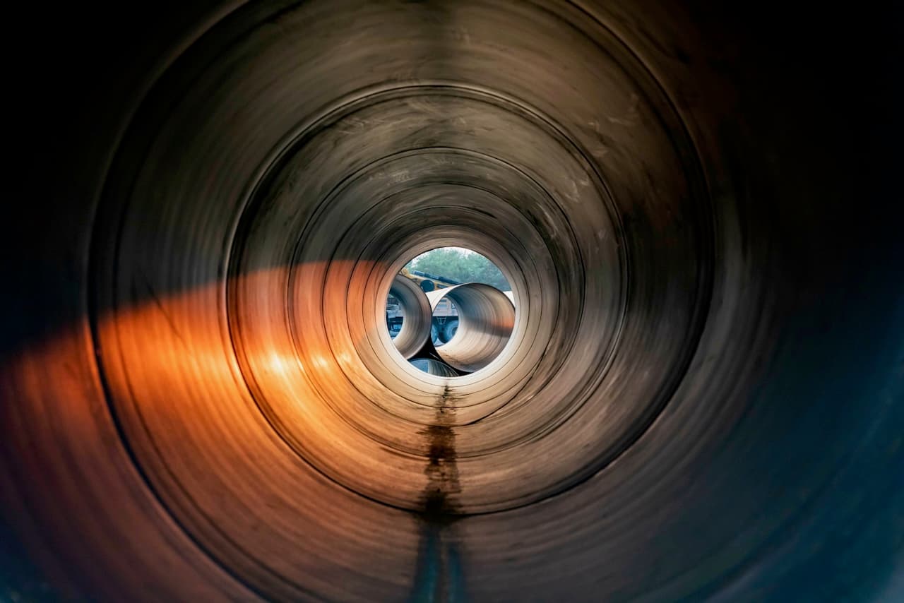 Interior de varios tubos de acero, mostrando un efecto de luz en su superficie y un enfoque en la profundidad del espacio.