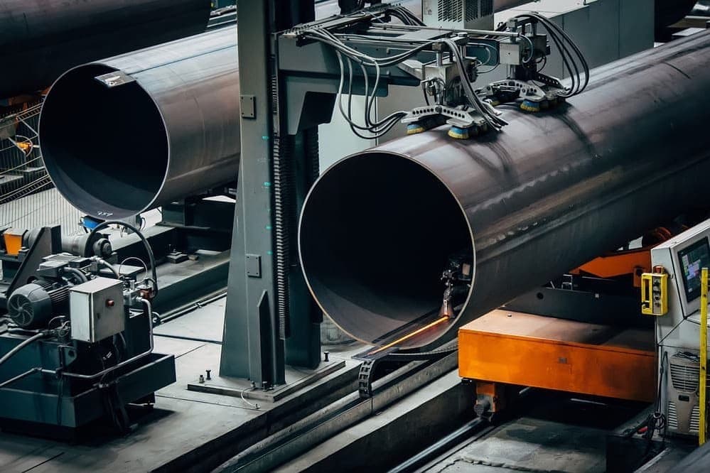 Proceso de fabricación de tubos de acero en una planta industrial con maquinaria avanzada.