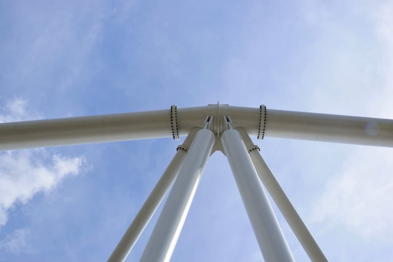 Estructura metálica de tubos que se unen en un punto, con un cielo claro de fondo.