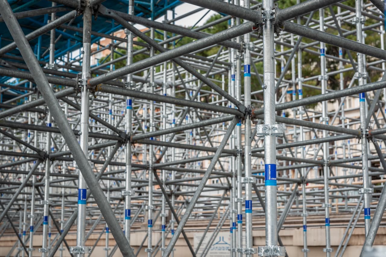 Estructura de andamios metálicos en un sitio de construcción, con múltiples tubos y conexiones visibles.